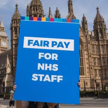 A Fair Pay for NHS staff sign is held up by a union representative in Westminster