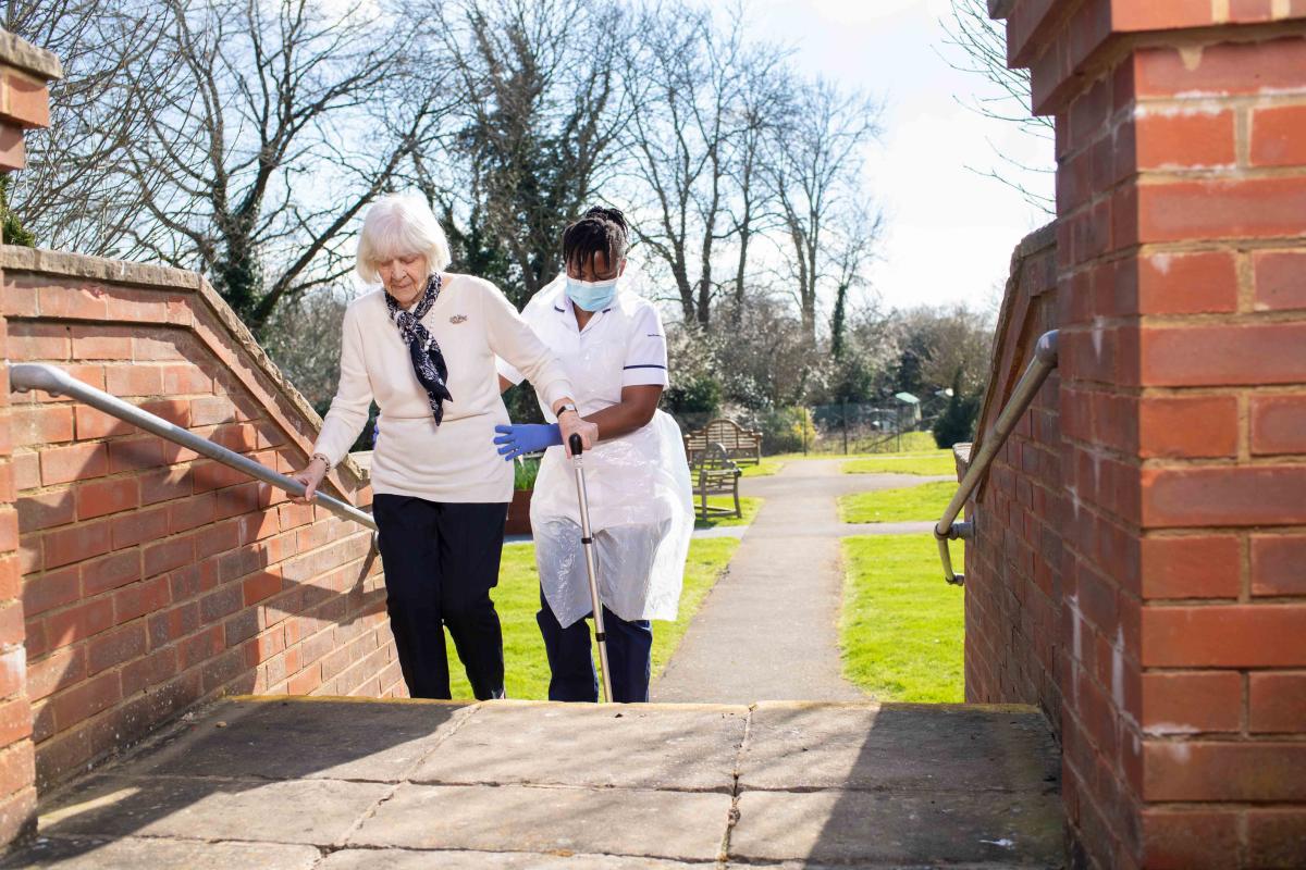 physio helps elderly patient on stairs rehab