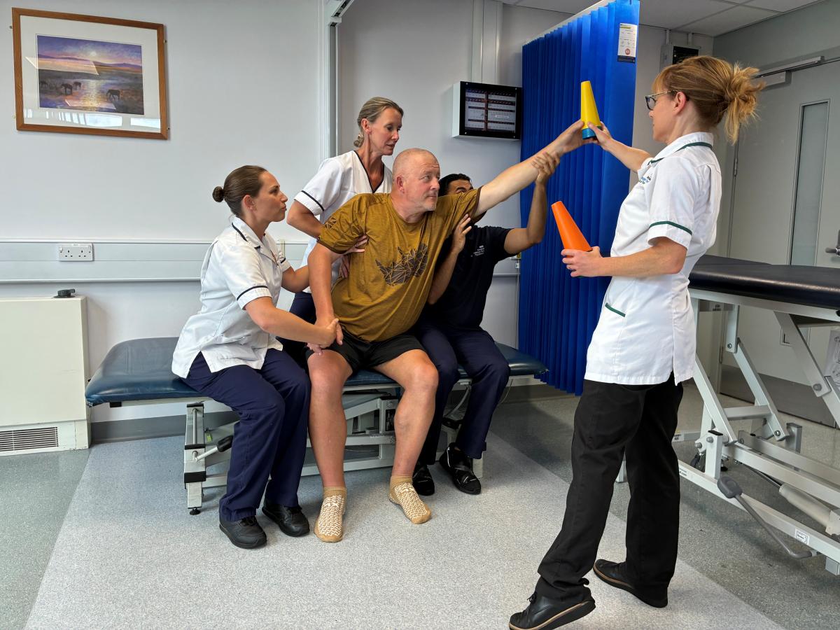 A stroke patient practices balance with a rehab team